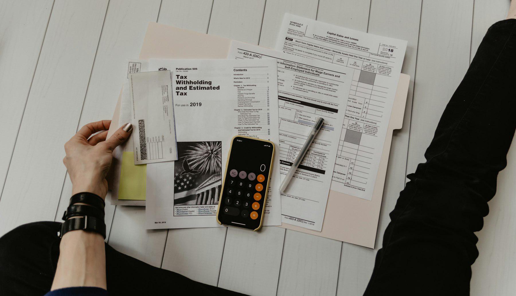 Person reviewing tax forms with a calculator