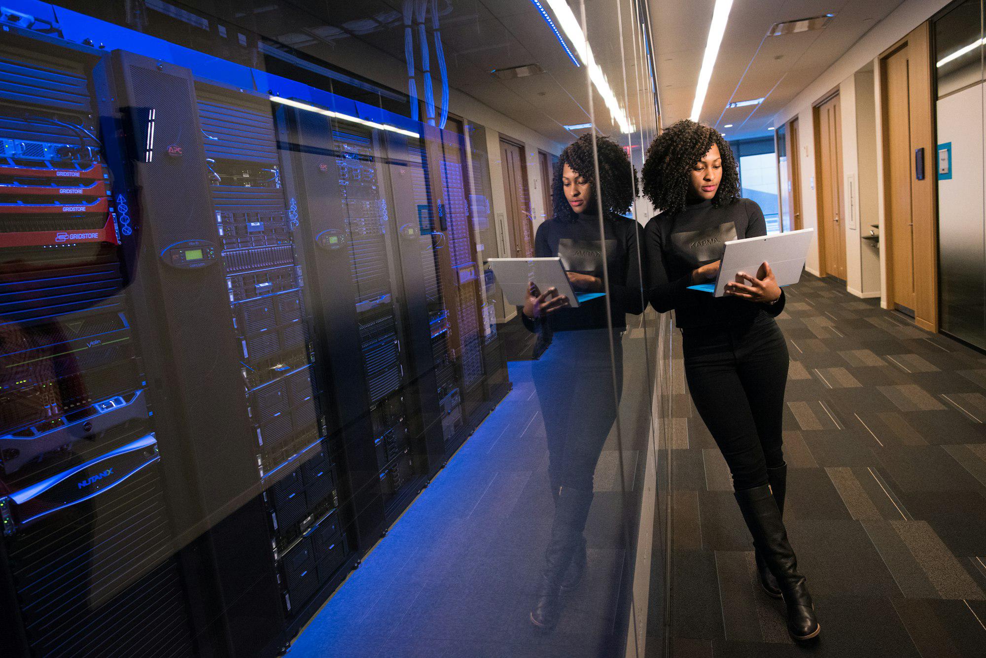Professional reviewing work on a laptop in a modern office corridor